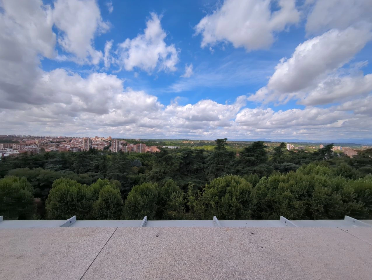 A wide Madrid city view stretches beyond treetops beneath broken cloud, illustrating how weather can shape photoshoot light.