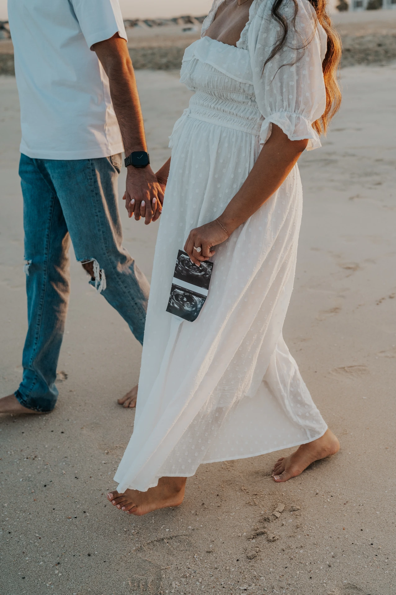 Close-up of an ultrasound print held during a Dubai beach maternity photoshoot, capturing a personal storytelling detail near the shoreline.