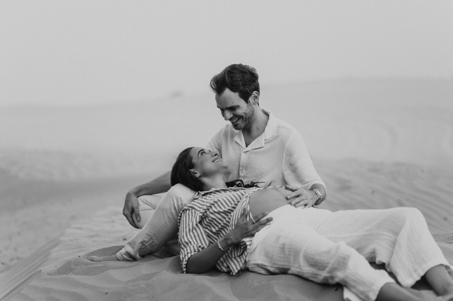 A maternity photoshoot in Dubai where the image is cropped on the couple and the belly, with the sea in the background. 