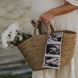 Pregnant woman holding basket with flowers and baby ultrasound photos during maternity photoshoot in Dubai