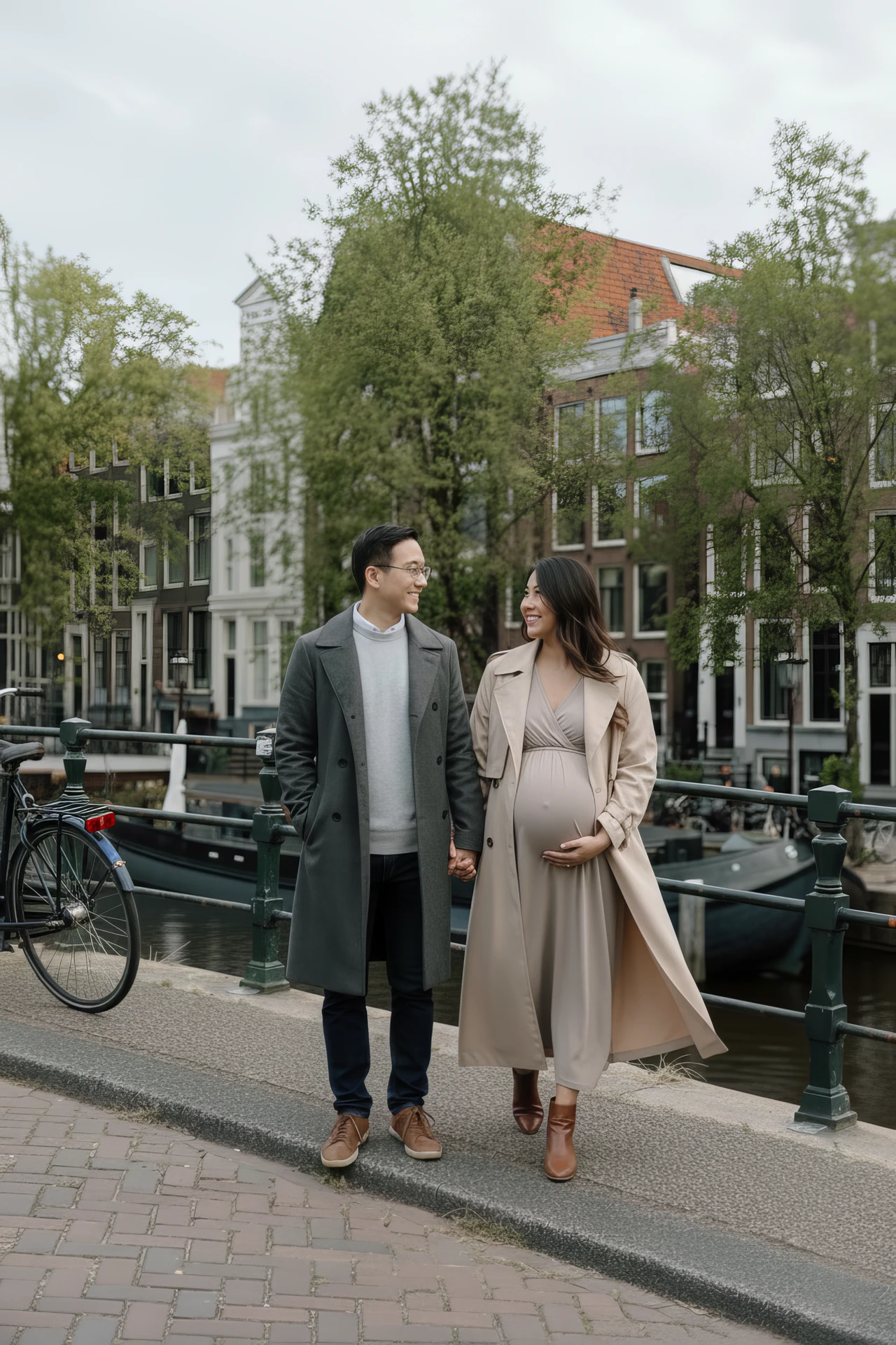 A couple smiling at each other during a maternity photoshoot in Amsterdam, with canals and classic city views.