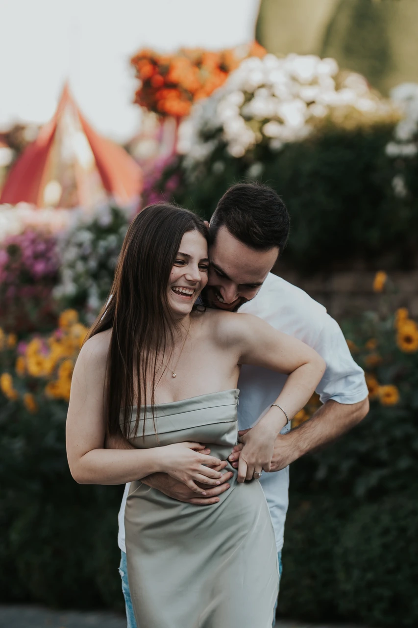 Photoshoot in Miracle Garden Dubai - close embrace portrait Close portrait of a couple embracing and laughing among colorful flowers in Dubai Miracle Garden during a photoshoot.