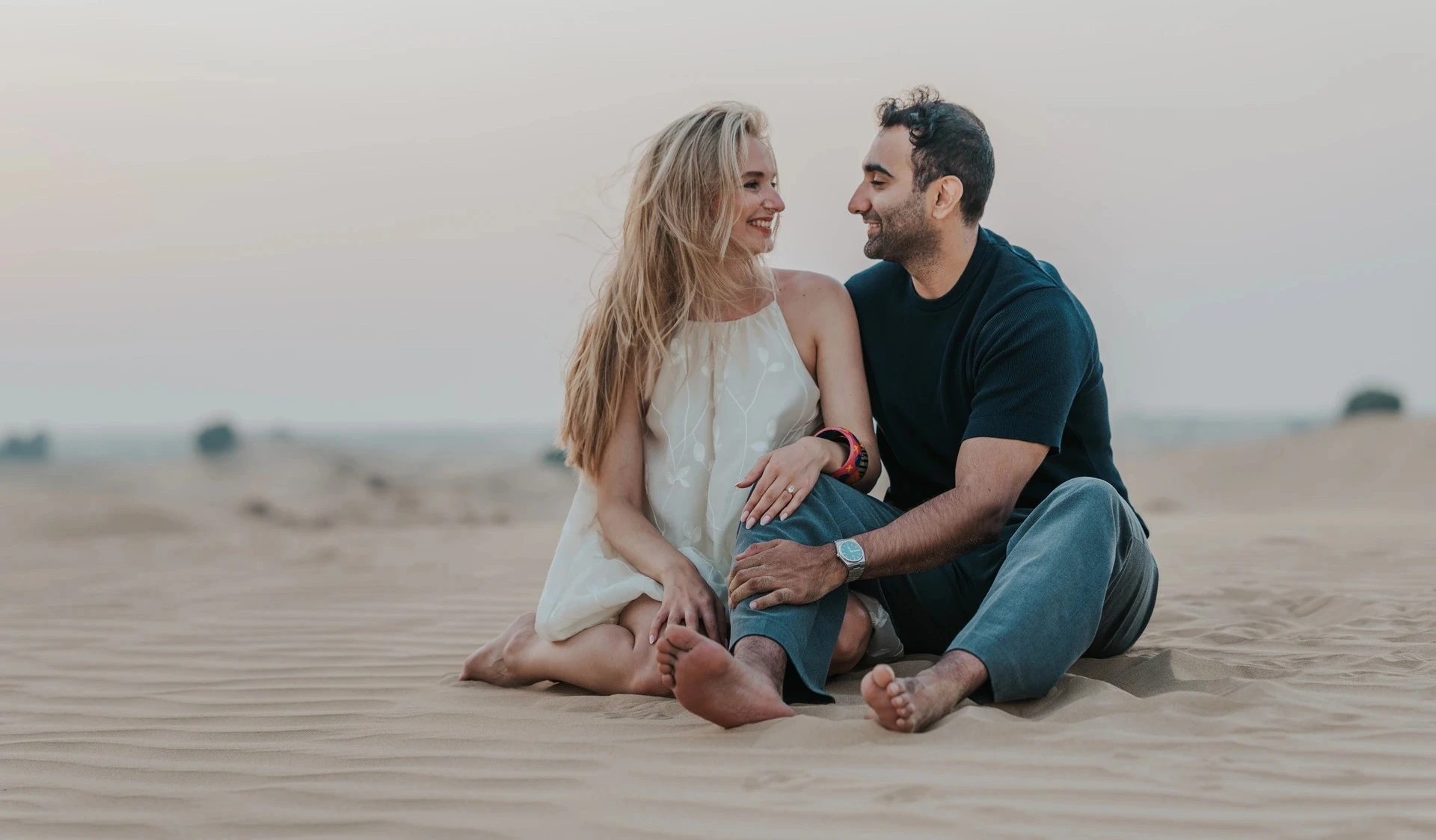 Couple sitting on Dubai dunes during candid couple photoshoot planning
