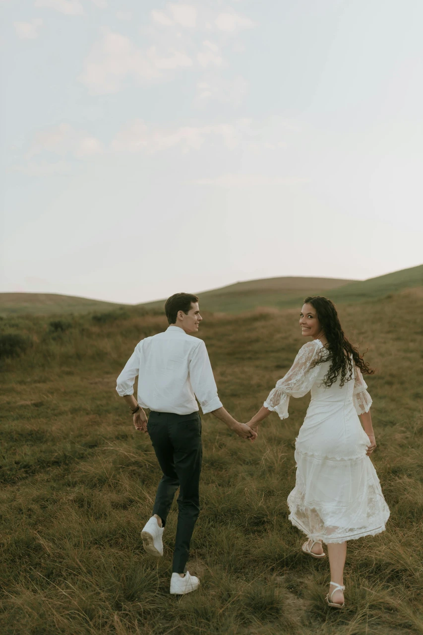 Engagement layers that look good and keep you warm Couple walking hand in hand in hills wearing warm engagement outfits