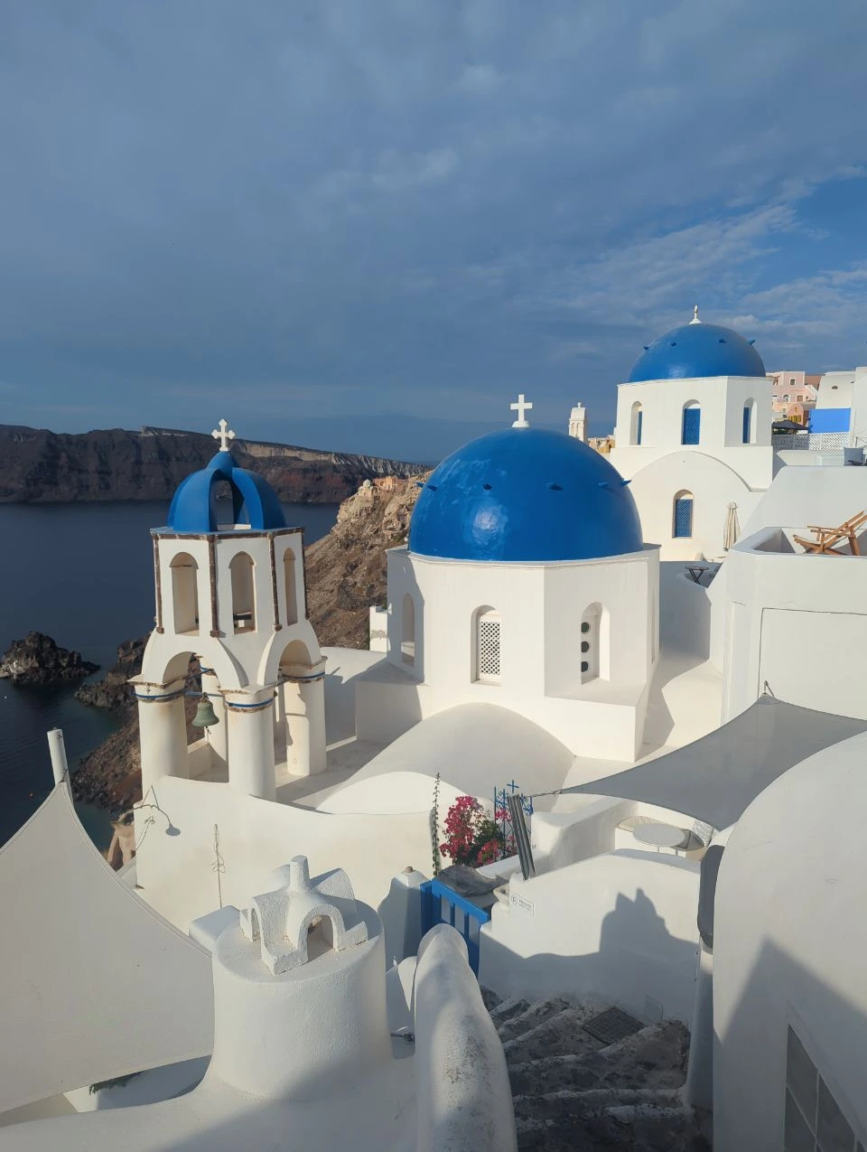 Oia blue domes and caldera | Santorini photo spots Blue-domed churches and a bell tower above white Oia rooftops, with the Santorini caldera behind them