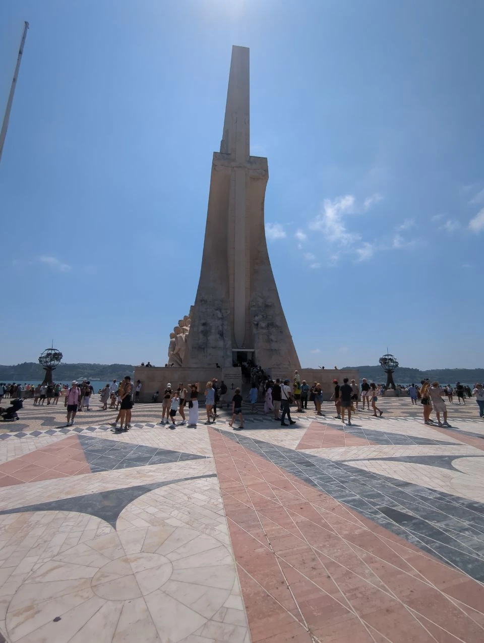 Visitors gather around Padrão dos Descobrimentos, where patterned paving leads toward the tall waterfront monument in Belém.