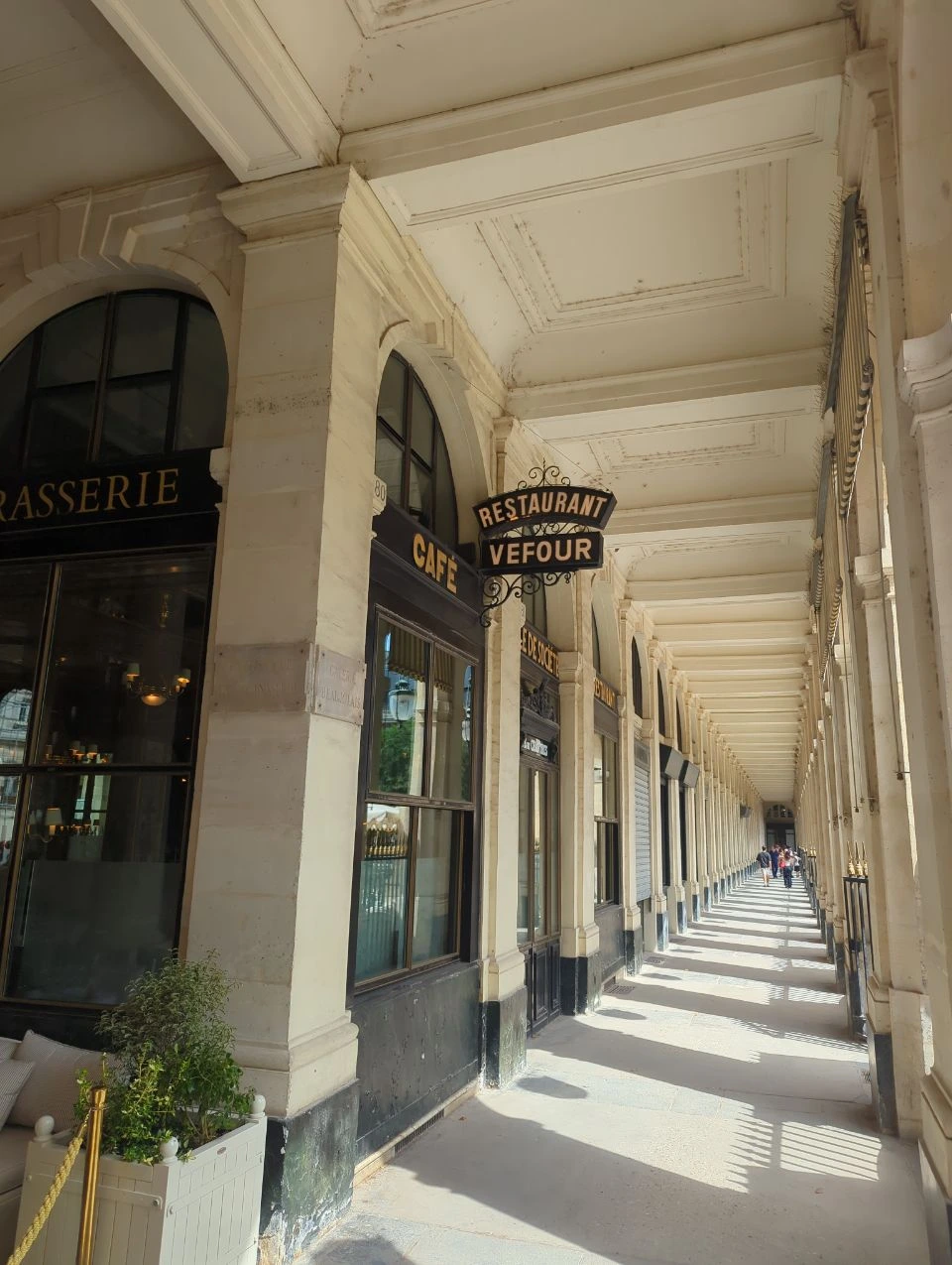 Paris Photo Spots - Palais Royal Arcade Sunlight and repeating columns draw the eye through a Palais Royal arcade in Paris, a sheltered architectural photoshoot setting.