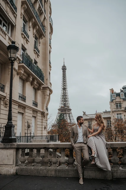 A couple’s portrait in Paris Couple sitting together on a stone balustrade with the Eiffel Tower behind them