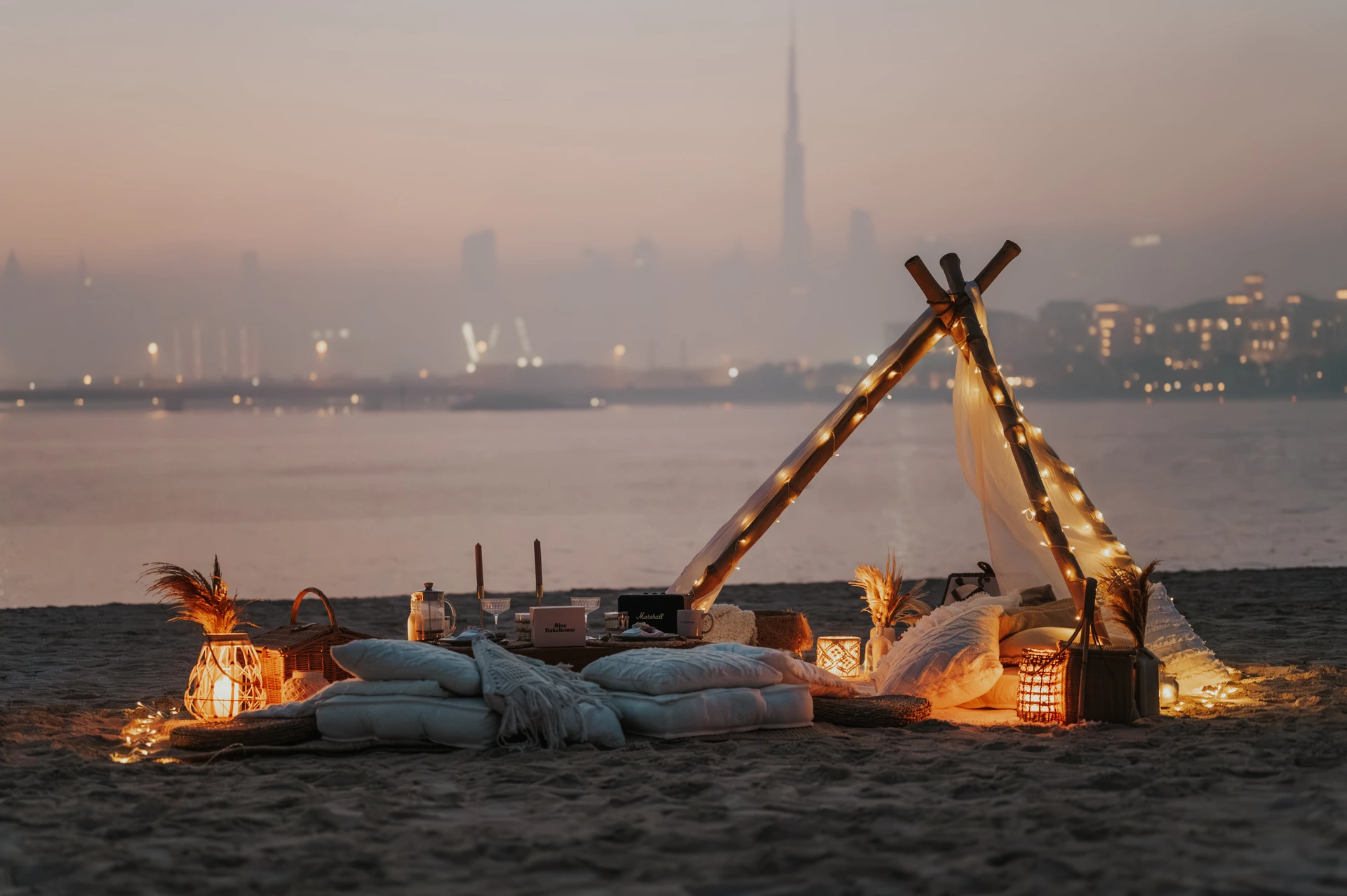 Une mise en scène de demande en mariage à Dubaï au coucher du soleil, sur la plage, avec la skyline et le Burj Khalifa en arrière-plan.