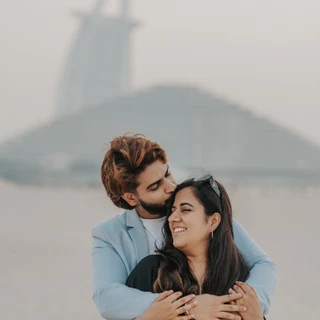 Un couple heureux photographié par un photographe de demande en mariage à Dubaï, avec le Burj Al Arab en arrière-plan.