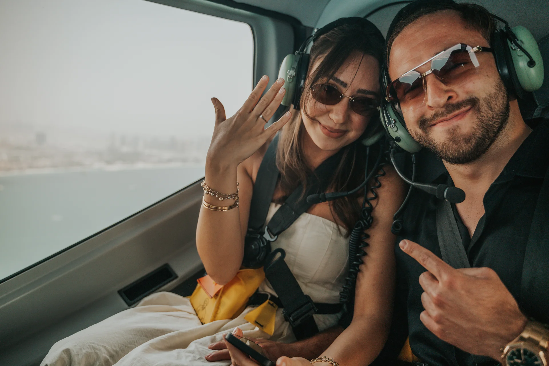 Dubai Helicopter Proposal Ring Reveal A couple wears aviation headsets inside a helicopter while the woman displays her ring after a Dubai proposal.