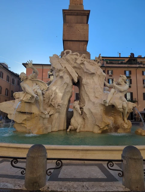 Piazza Navona Fountain Carved stone figures and a tall obelisk rise from a fountain in Piazza Navona, Rome.