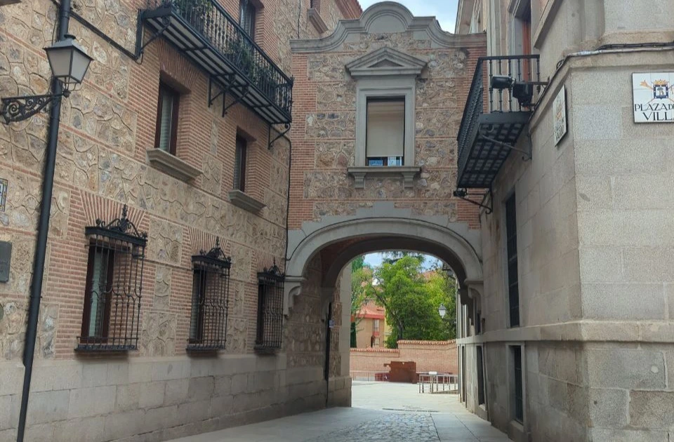 An empty arched passage between historic buildings at Plaza de la Villa opens this Madrid photoshoot route.