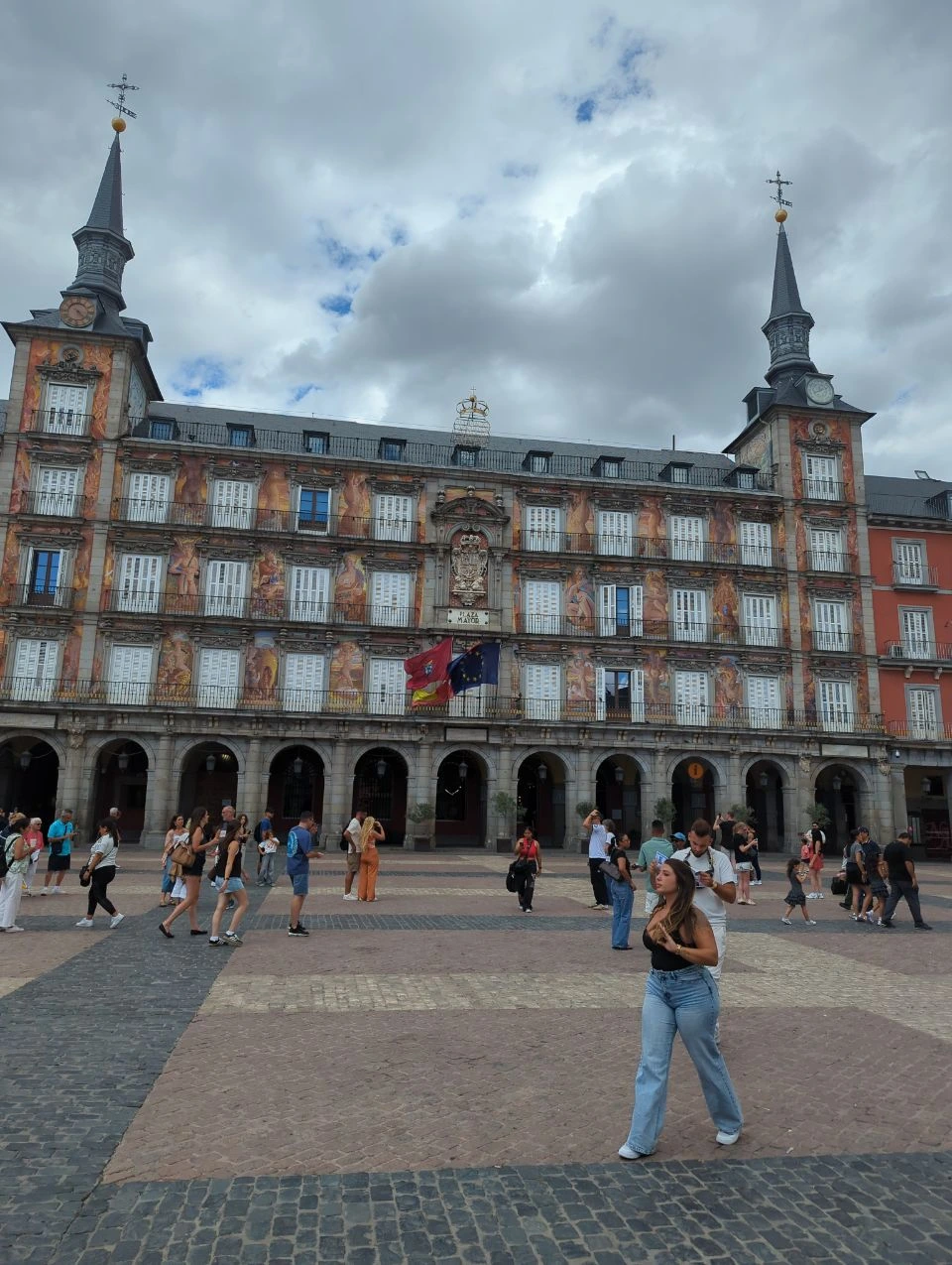 Madrid Photoshoot Timing - Plaza Mayor Visitors cross Plaza Mayor beneath its painted facade and shaded arcades, showing the busy side of a Madrid photoshoot location.