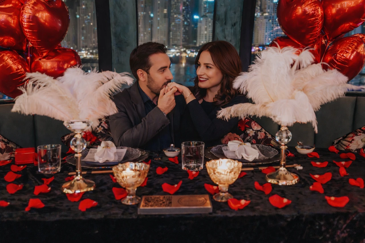 Proposal at the Pods in Dubai - Private pod dinner setup A couple sits together inside a decorated private pod with rose petals, red balloons, and city lights in the background.