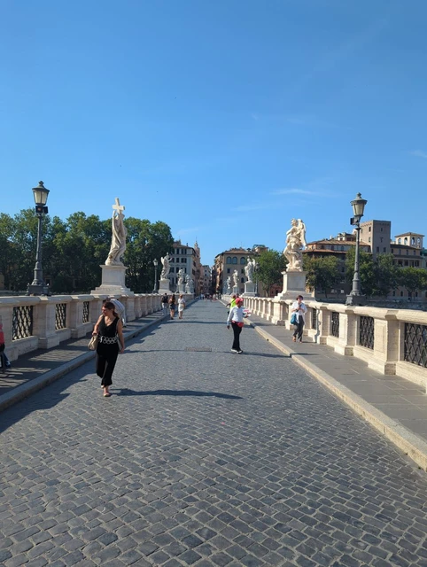 Ponte Sant’Angelo Walking Route A pedestrian walks along the cobbled Ponte Sant’Angelo, with angel statues, stone balustrades and Castel Sant’Angelo ahead.