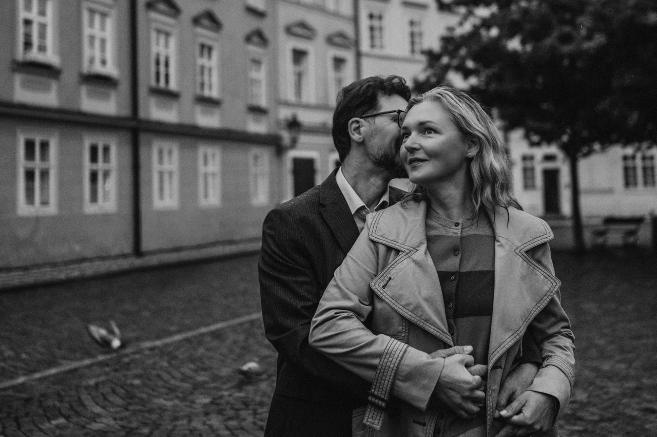 Black-and-white Prague anniversary photoshoot in Kampa Black-and-white landscape portrait of a cheek kiss and a smile in Kampa during the couple's Prague anniversary photoshoot.