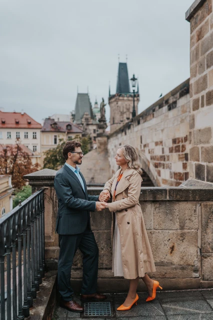 Prague anniversary photoshoot on the Kampa stair landing Couple facing each other and holding hands on a stair landing beside Charles Bridge during their Prague anniversary photoshoot.