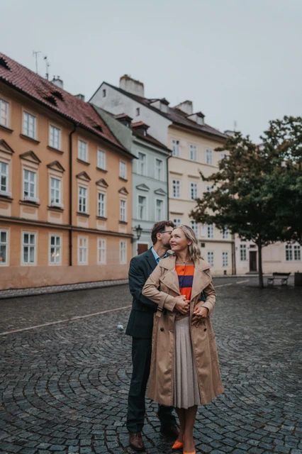 Couple sharing an embrace in front of Kampa's yellow houses during their anniversary photoshoot in Prague.
