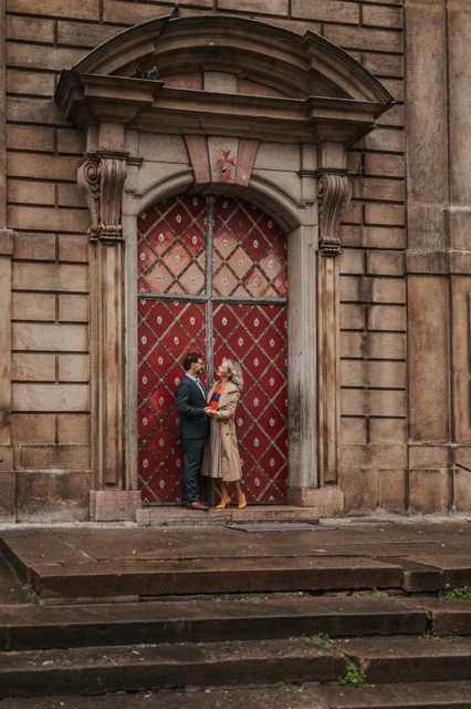 Prague anniversary photoshoot with an embrace at a red doorway Couple embracing in front of an ornate red doorway in Old Town during their anniversary photoshoot in Prague.