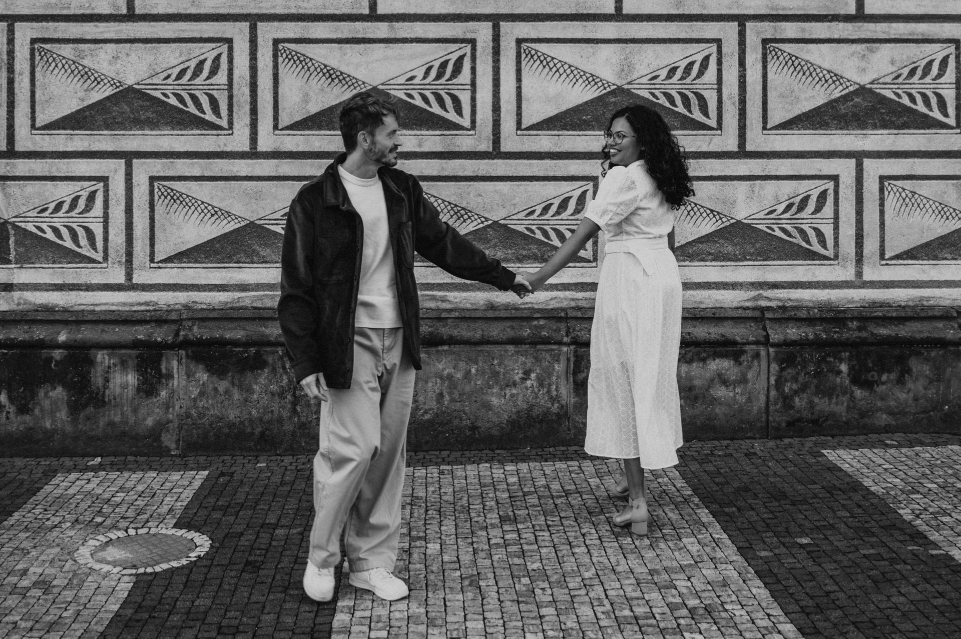 Black and white portrait beside the decorated castle-area wall during an anniversary couple photoshoot in Prague.