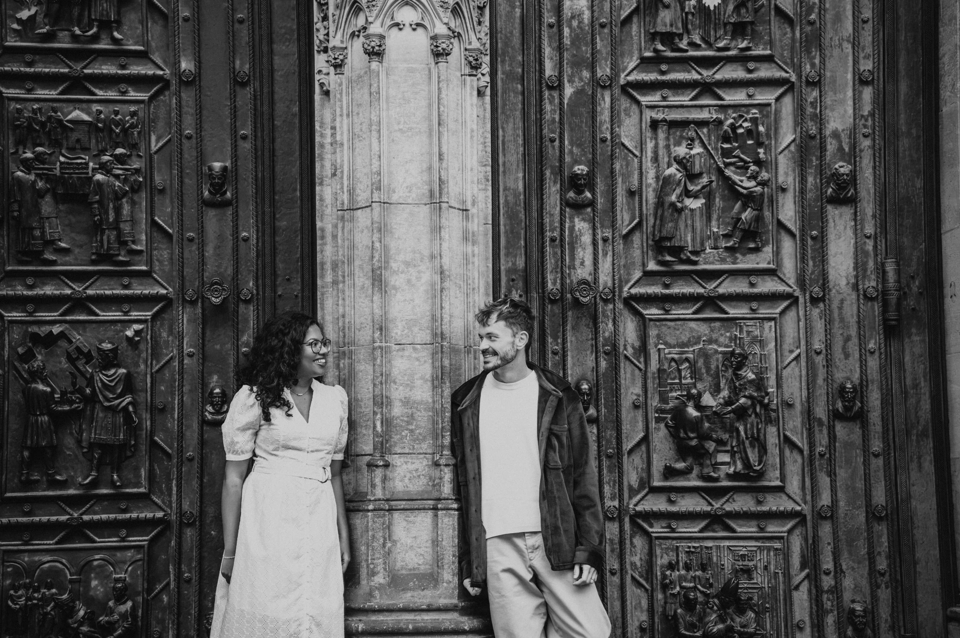 Black and white portrait of the couple beside the cathedral doors during an anniversary couple photoshoot in Prague.