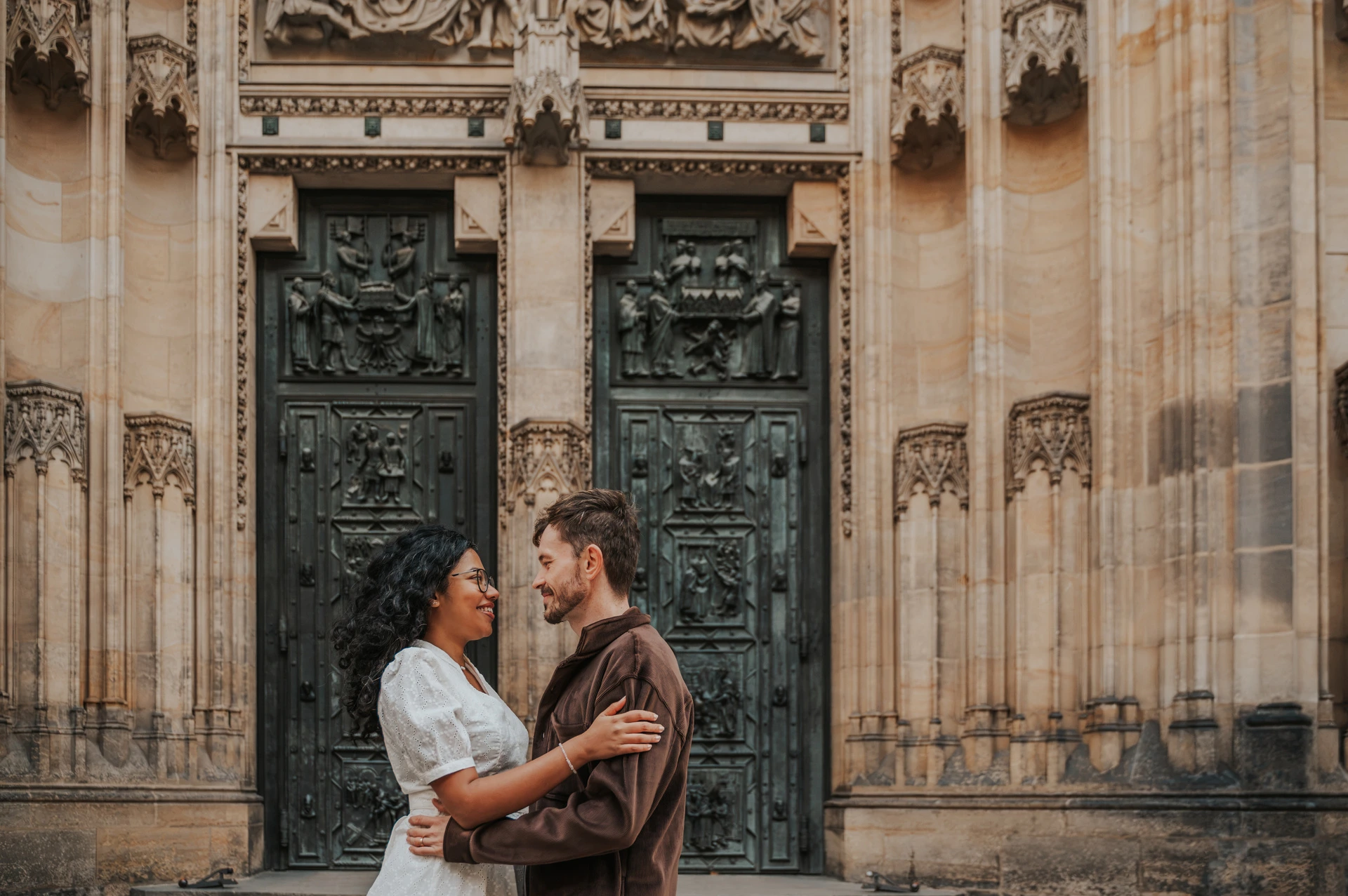 Couple embracing in front of the cathedral doors during an anniversary couple photoshoot in Prague.