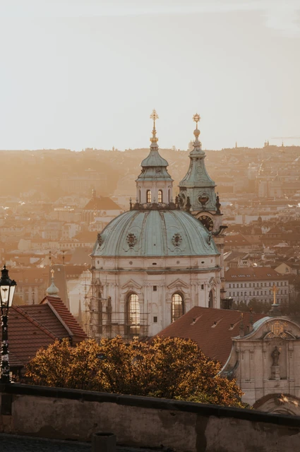 Couple embracing with the city rooftops and domed church behind them during an anniversary couple photoshoot in Prague.
