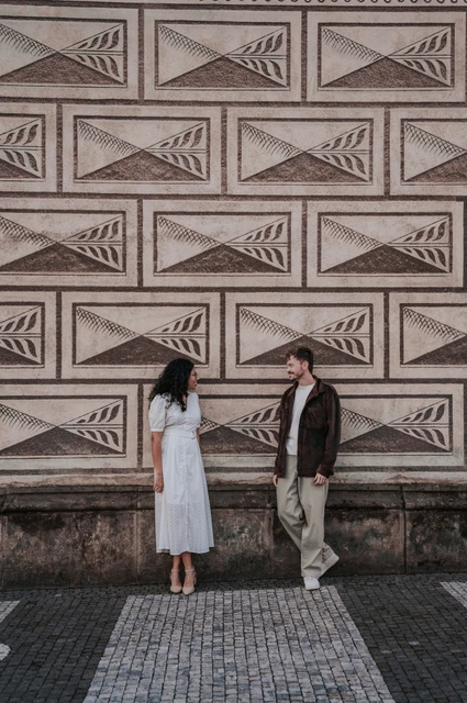 Prague anniversary photoshoot: couple holding hands against a patterned wall near Prague Castle. Couple holding hands against a patterned wall near Prague Castle during an anniversary couple photoshoot in Prague.