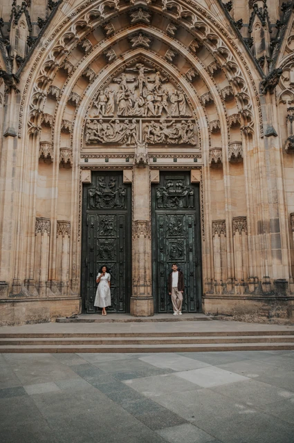 Prague anniversary photoshoot: couple holding hands beneath the ornate cathedral doorway. Couple holding hands beneath the ornate cathedral doorway during an anniversary couple photoshoot in Prague.