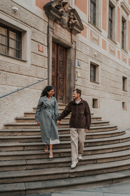 Couple holding hands while walking down steps at Prague Castle during an anniversary couple photoshoot in Prague.