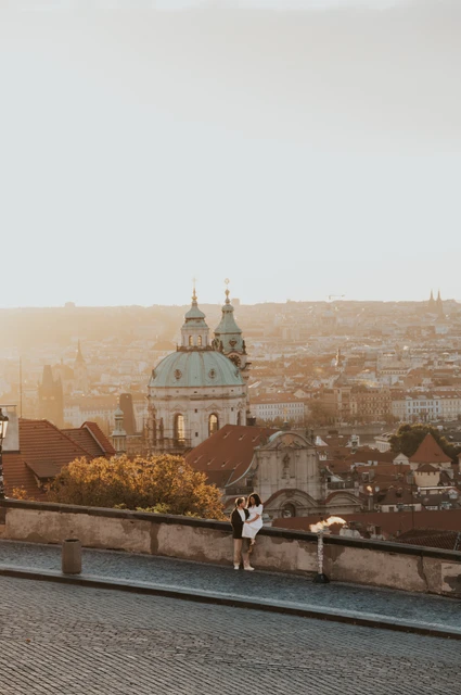 Prague anniversary photoshoot: couple looking out across Prague from the stone viewpoint wall. Couple looking out across Prague from the stone viewpoint wall during an anniversary couple photoshoot in Prague.
