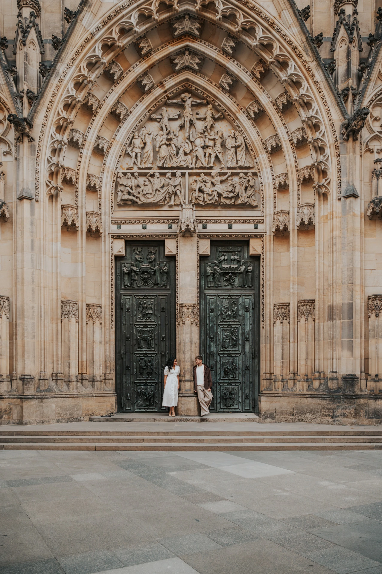 Couple standing beneath a carved cathedral arch at Prague Castle during an anniversary couple photoshoot in Prague.
