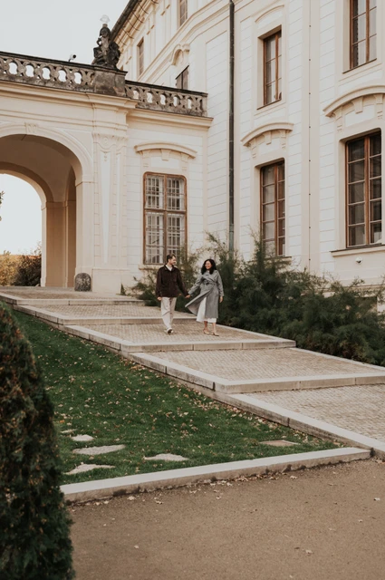 Couple walking along a path beside the castle buildings during an anniversary couple photoshoot in Prague.