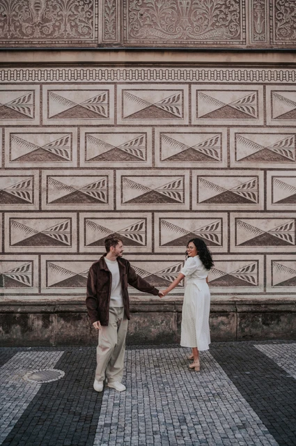 Prague anniversary photoshoot: couple walking hand in hand past the decorated wall. Couple walking hand in hand past the decorated wall during an anniversary couple photoshoot in Prague.