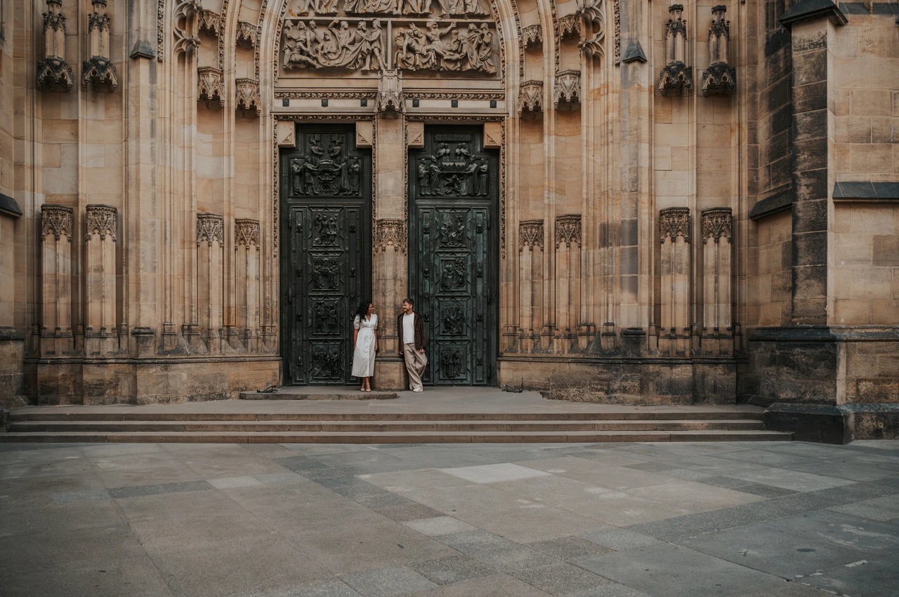 Prague anniversary photoshoot: wide portrait of the couple outside the cathedral doors. Wide portrait of the couple outside the cathedral doors during an anniversary couple photoshoot in Prague.