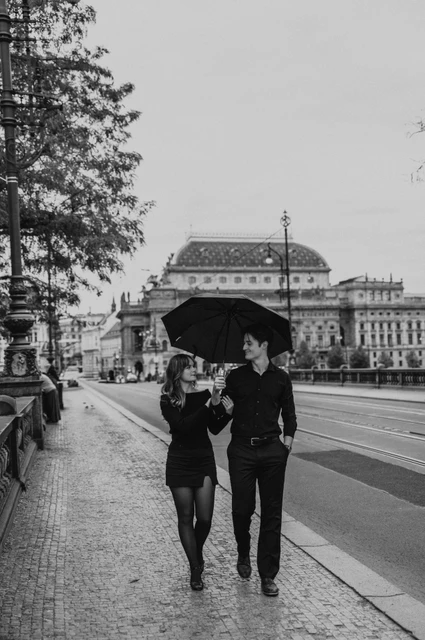 Prague couple photoshoot: black and white portrait of the couple walking under an umbrella. Black and white portrait of the couple walking under an umbrella during a couple photoshoot in Prague.