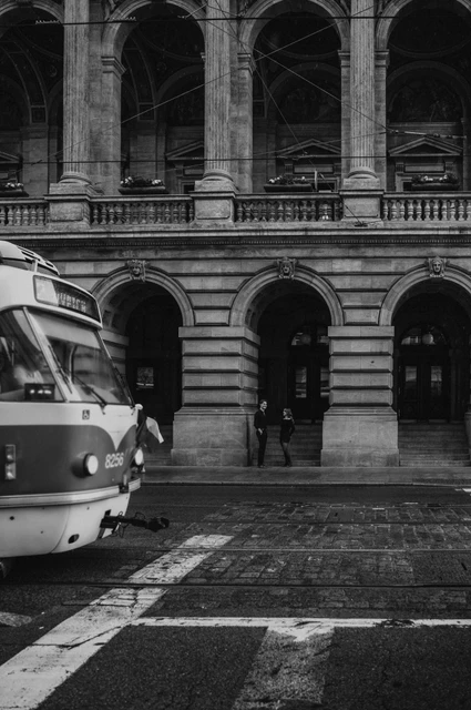 Prague couple photoshoot: black and white theatre portrait with a passing tram. Black and white theatre portrait with a passing tram during a couple photoshoot in Prague.