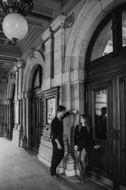 Prague couple photoshoot: black and white walk beneath the National Theatre arcade. Black and white walk beneath the National Theatre arcade during a couple photoshoot in Prague.