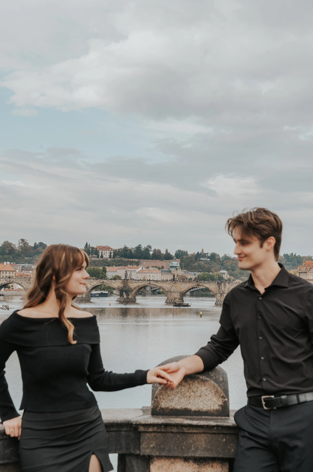 Close portrait of the couple holding hands above the river during a couple photoshoot in Prague.