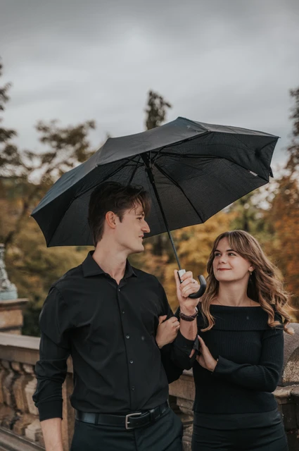 Prague couple photoshoot: couple exchanging smiles while sharing an umbrella. Couple exchanging smiles while sharing an umbrella during a couple photoshoot in Prague.