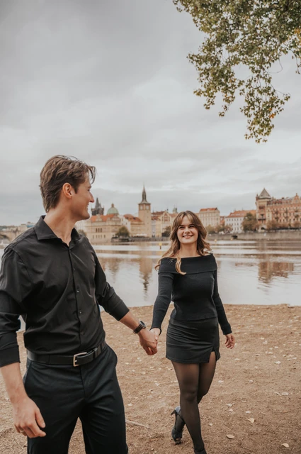 Prague couple photoshoot: couple holding hands beside the island riverbank. Couple holding hands beside the island riverbank during a couple photoshoot in Prague.