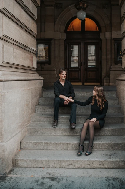 Couple holding hands on the National Theatre entrance steps during a couple photoshoot in Prague.
