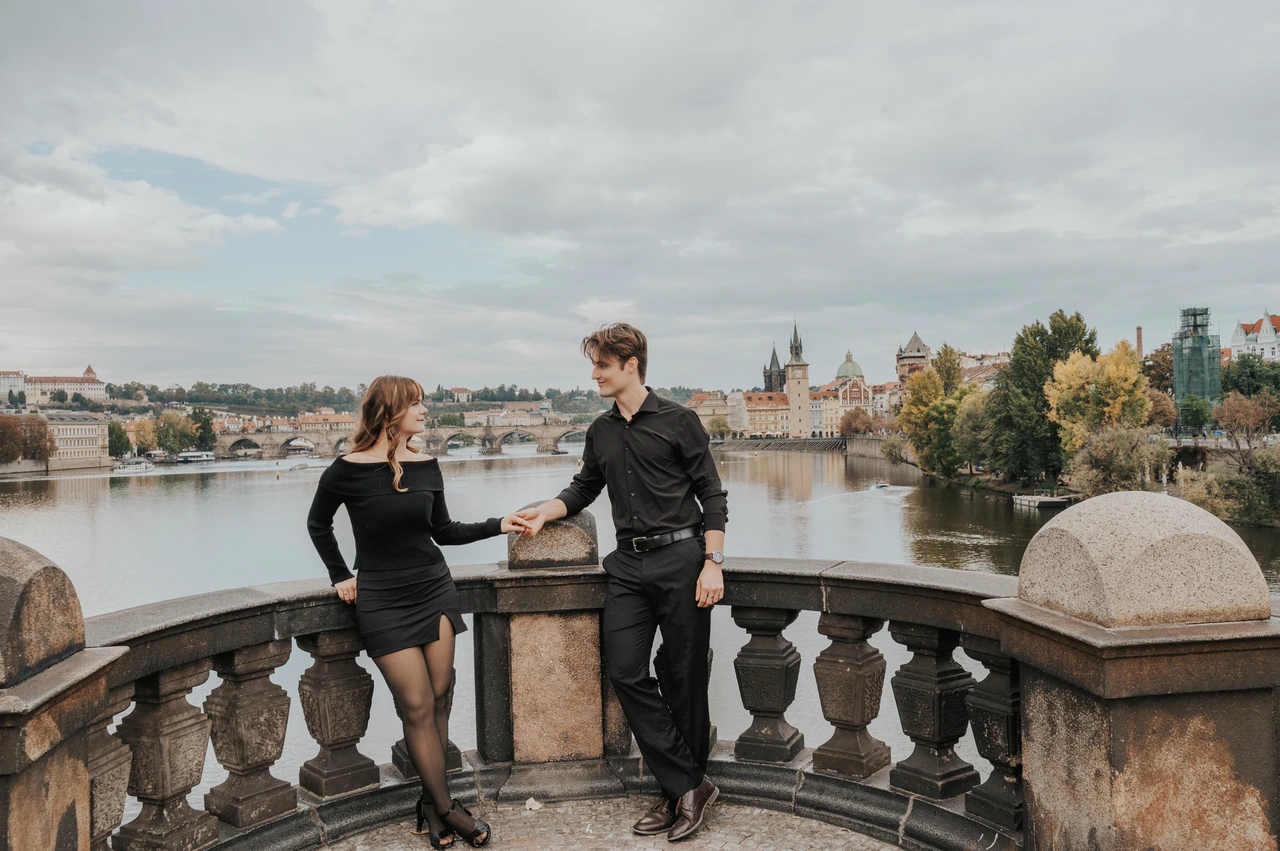Prague couple photoshoot: couple reaching for each other beside the bridge railing. Couple reaching for each other beside the bridge railing during a couple photoshoot in Prague.