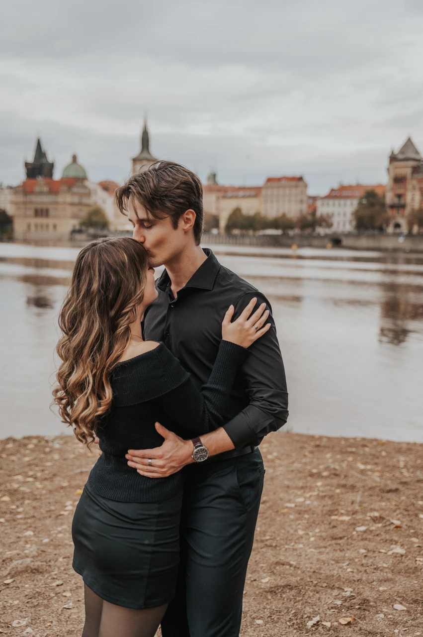 Prague couple photoshoot: couple sharing a kiss beside the water on Shooter’s Island. Couple sharing a kiss beside the water on Shooter’s Island during a couple photoshoot in Prague.