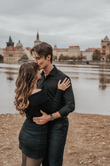 Prague couple photoshoot: couple sharing a kiss beside the water on Shooter’s Island. Couple sharing a kiss beside the water on Shooter’s Island during a couple photoshoot in Prague.
