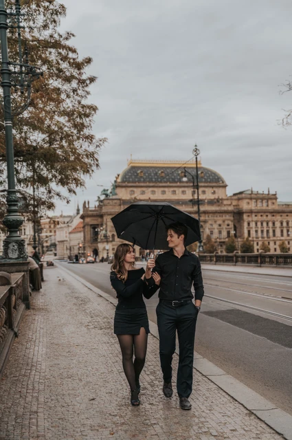 Prague couple photoshoot: couple smiling beneath an umbrella on Legion Bridge. Couple smiling beneath an umbrella on Legion Bridge during a couple photoshoot in Prague.