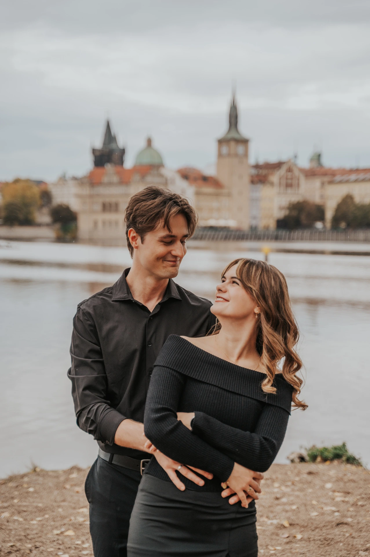 Couple smiling together on the island riverbank during a couple photoshoot in Prague.