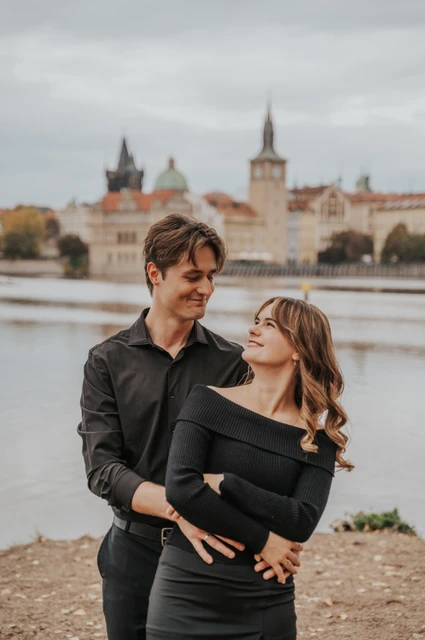 Prague couple photoshoot: couple smiling together on the island riverbank. Couple smiling together on the island riverbank during a couple photoshoot in Prague.