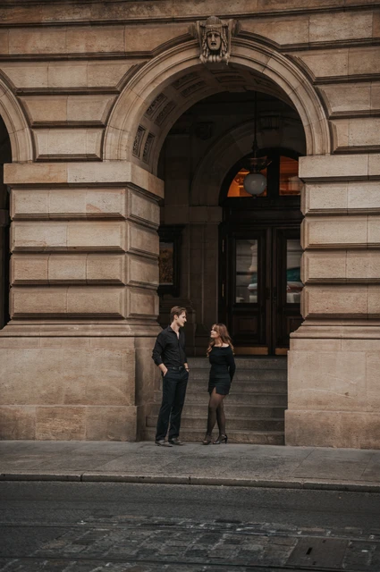 Prague couple photoshoot: couple standing beside an arched theatre entrance. Couple standing beside an arched theatre entrance during a couple photoshoot in Prague.